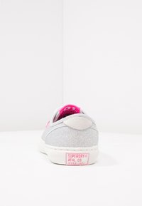 Sneaker grigio con glitter e dettagli rosa, dotato di una parte posteriore testurizzata, suola bianca e un'etichetta con il logo sul tallone.