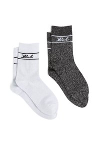 Deux paires de chaussettes : une blanche et une noire, toutes deux avec des rayures horizontales noires et un tissu texturé avec un léger éclat.