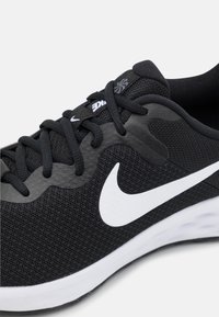 Mustan värvi sportlik king, millel on tekstuuriga kangas pealispind, pehmendustega kaelus ja valge Nike logo. Omab musti nööre ja kummist talda.