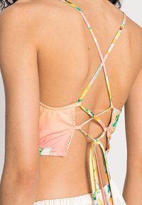 Top bikini colorato con un motivo floreale, dotato di sottili spalline incrociate sul retro, tessuto morbido e lacci regolabili sul retro per una vestibilità sicura.