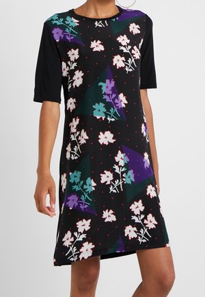Zwarte jurk tot op de knie met halflange mouwen, voorzien van witte, paarse en turquoise bloemenpatronen en kleine rode stippen als accenten.