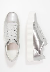 Zilverkleurige metallic sneakers met een gladde afwerking, gestructureerde zijpanelen en witte gegroefde zolen. Voorzien van platte grijze veters en gestikte accenten.