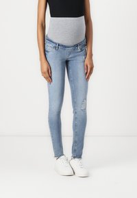 Jeans skinny de maternidad en denim azul claro con un panel elástico gris en la barriga, que presenta acentos desgastados y un diseño ajustado.