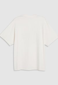 Camiseta blanca de manga corta y corte oversize, hecha de algodón suave. Textura lisa con cuello redondo y dobladillo recto, diseño minimalista y versátil.