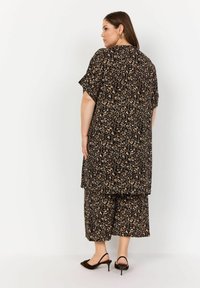 Svart och tan leopardmönstrad tvådelad outfit med lös topp och vida byxor, som har en avslappnad passform och lättviktig tyg.