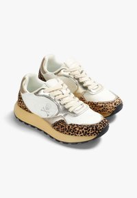 Zapatillas blancas con acentos de estampado de leopardo, detalles metálicos y suela de goma beige. Presenta un diseño de cordones y un logo de calavera en el lateral.
