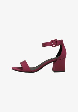 Purple block-heeled sandals with a narrow ankle strap and open toe. Features a smooth matte finish and a geometric heel design.