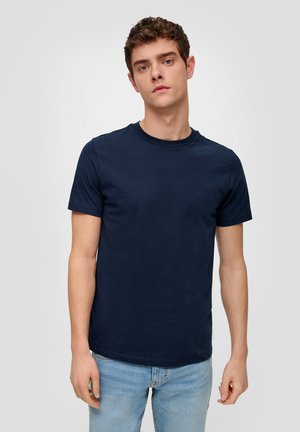 Camiseta de algodón azul marino con mangas cortas, cuello redondo y un corte clásico. Combinada con pantalones vaqueros de color azul claro, diseño minimalista y textura suave.