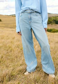 Svetlomodré široké rifle vyrobené z denimu, s vysokým pásom, prednými vreckami a mierne vybledlým vzhľadom pre ležérny štýl.