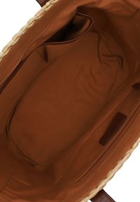 Interieur van een geweven draagtas, met een gladde bruine voering, leren accenten en een ritsvak aan één kant voor opbergruimte.