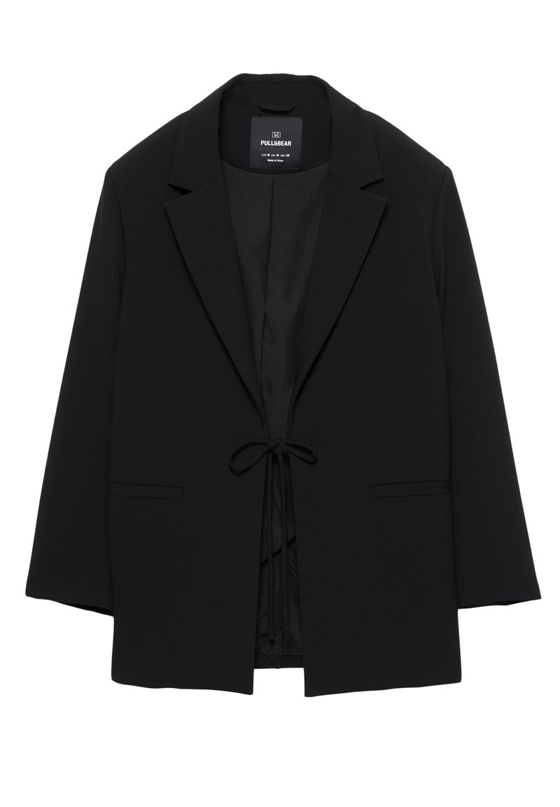Blazer noir cintré avec revers, deux poches avant et une fermeture par nœud à la taille, présenté sur un fond blanc.