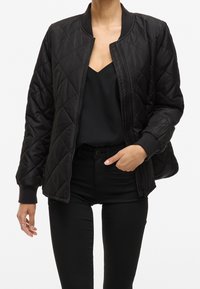 Černá prošívaná bomber bunda se zipem vpředu, žebrovanými manžetami a límcem. Disponuje hladkou texturou a detailem v podobě diamantového vzoru.