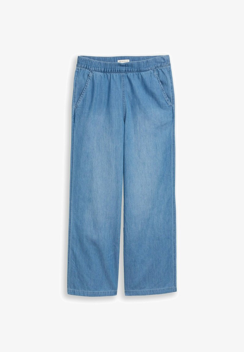 Šviesiai mėlynos spalvos platėjančios džinsinės kelnės su elastine juosmens juosta ir šoninėmis kišenėmis, išdėliotos ant balto fono.