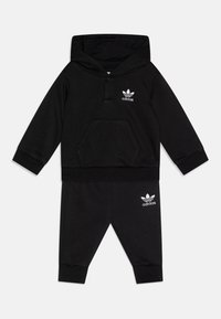 Tuta per bambini Adidas nera, composta da una felpa con cappuccio e tasca frontale e pantaloni abbinati, entrambi con accenti del logo bianco.