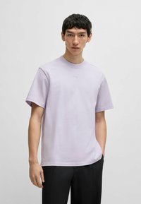 Tricou scurt cu mânecă, de culoare lavandă deschisă, cu decolteu rotund și detalii subtile cu logo pe piept, fabricat din material din bumbac, cu croi lejer.