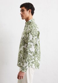 Lightweight linen shirt featuring a green floral pattern on a white background, long sleeves, collared neck, and buttoned cuffs.