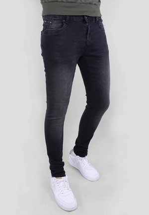 Mörkt tvättade skinny jeans av denim, med dragkedja fram, fem fickor och slitna detaljer, kombinerat med vita sneakers.