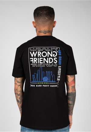 Camiseta de algodón negra con un diseño gráfico audaz que presenta texto en blanco y azul. Ilustración icónica del horizonte en el centro. Fit unisex.
