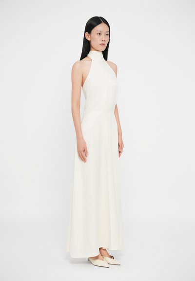 Rochie lungă, albă, cu guler halter, având un bust ajustat și o fustă fluidă. Țesătură netedă, design minimalist, asortată cu pantofi cu vârf ascuțit.