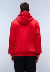 Felpa rossa con cappuccio, dal texture morbido, con un grande cappuccio sulla schiena e maniche lunghe. Presenta un design semplice con orlo e polsini a coste.