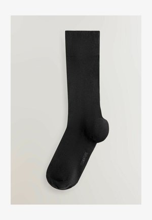 Černá ponožka z hladkého materiálu, s zesílenou patou a špičkou. Na vrcholu strukturovaný žebrovaný lem. Bez viditelných vzorů.
