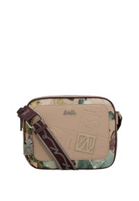 Beige und gemusterte rechteckige Umhängetasche mit verstellbarem braunem Trageriemen, geprägtem Vorderelement und metallicfarbenem Markenlogo sowie Charms.