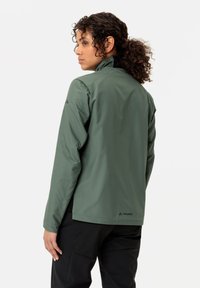 Giacca impermeabile verde con colletto alto, maniche lunghe e design minimalista. Presenta un logo sulla parte posteriore e una texture liscia.