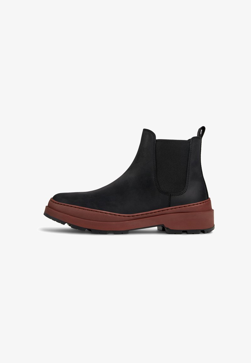 Schwarze Leder-Chelsea-Boots mit elastischen Seiteneinsätzen, runder Spitze und einer dicken, kastanienbraunen Gummiksohle, die über ein strukturiertes Profil für besseren Halt verfügt.