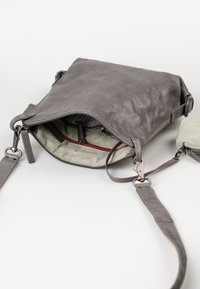 Graue Lederhandtasche mit einem Reißverschlussöffnung, ausgestattet mit einem gestreiften Innenfutter und einem kleinen abnehmbaren Täschchen. Akzentuiert mit Metallbeschlägen und einem stabilen Tragegurt.