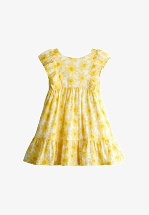 Sárga és fehér ujjatlan kisgyermek ruha fodros ujjakkal és szegéllyel, vidám nagy margaréta mintákkal díszítve.
