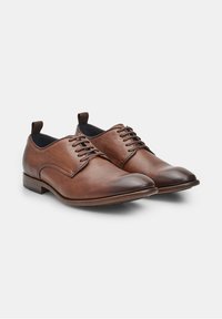 Scarpe eleganti in pelle marrone con una texture liscia, punta arrotondata e design con lacci. Presentano un tacco basso a strati e dettagli di cucitura discreti.