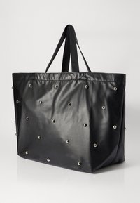 Black faux leather tote bag with silver studs, flat shape, long handles, smooth texture, and a simple design. Dimensions not specified.