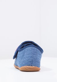 Niebieski dżinsowy but z teksturowaną górą, zaokrąglonym kształtem, elastyczną gumową podeszwą oraz granatowym materiałowym wykończeniem wokół kołnierza dla większego komfortu.