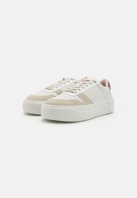Baskets blanches en cuir avec des accents en daim beige, bout rond et semelle plateforme épaisse. Lacets beige et accent de talon bordeaux.