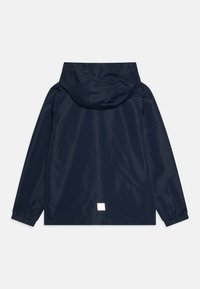 Marinblå vattentät jacka med huva, elastiska ärmslut, rak passform och en liten fyrkantig logotyp i nederkant på baksidan.