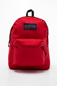 Sac à dos en nylon rouge avec une poche avant, des bretelles réglables et une poignée supérieure. Présente un patch de logo Jansport bleu. Texture lisse, forme arrondie.
