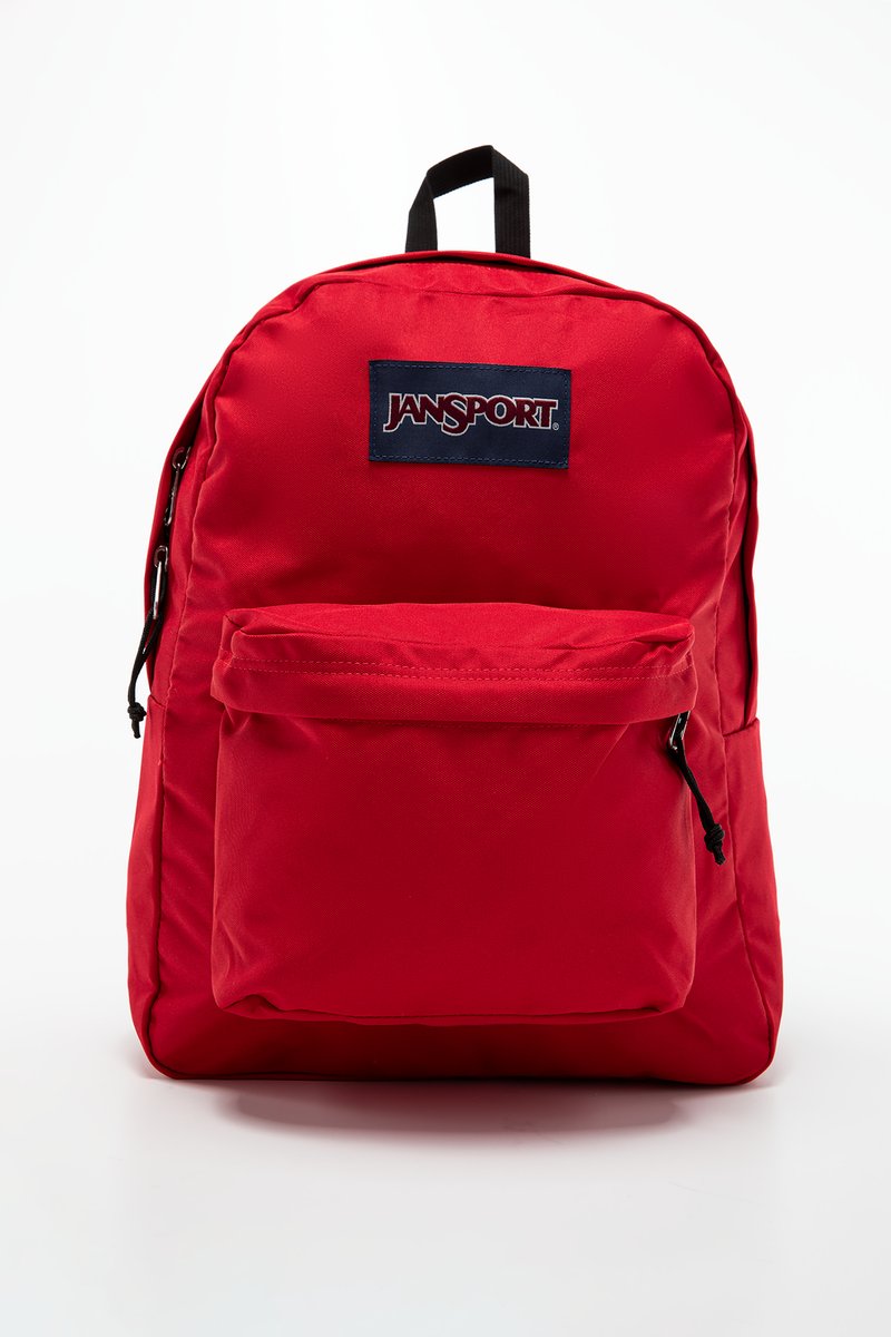 Sac à dos en nylon rouge avec une poche avant, des bretelles réglables et une poignée supérieure. Présente un patch de logo Jansport bleu. Texture lisse, forme arrondie.