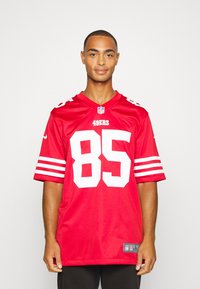 Piros NFL mez fehér kiegészítőkkel, rajta a 85-ös szám és a csapat neve. Rövid ujjak, kerek nyakú, sima anyagból készült, logókkal díszítve.