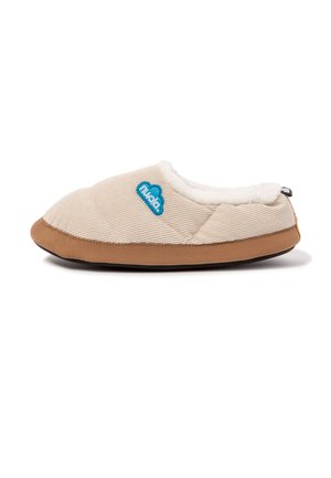 Zapatilla beige acolchada con suela marrón y forro blanco y peludo, con un logo azul con forma de nube en el lateral y una pequeña lengüeta trasera.