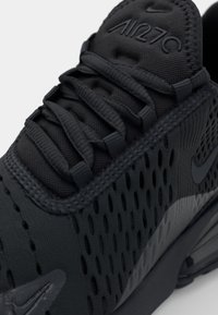 Černé tenisky Nike Air Max 270 mají síťový svršek s ventilačními otvory, texturované tkaničky a polstrovaný jazyk s embosovaným názvem značky.