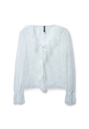 Blouse en dentelle blanche avec des manches longues légèrement bouffantes, encolure en V et fermeture à nouer. Présente un motif floral délicat et un tissu texturé.