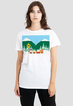 White t-shirt featuring a graphic design of four cartoon characters in front of green mountains and pine trees, with a yellow warning sign.