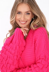 Světle růžový pletený svetr s volnými, texturovanými rukávy a výstřihem ve tvaru V. Disponuje silnou, pohodlnou pleteninou po celém povrchu.