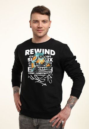 Sort sweatshirt med et grafisk design, der fremhæver en animeret karakter og fed hvid tekst. Lange ærmer og afslappet pasform. Blødt stof.