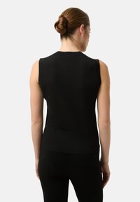 Schwarzes ärmelloses Strickoberteil mit tailliertem Schnitt, gerippter Struktur und flachem Saum, kombiniert mit schwarzen Leggings. Rückansicht betont die Schlichtheit.