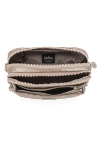 Kipling handbag in light beige nylon, featuring multiple zippered compartments and the brand label inside. Smooth texture, compact design.