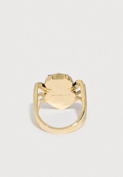 Kullast ämbliku sõrmus, millel on läikiv viimistlus, keerukad jaladetailid ja südamekujuline alus, graveeringuga sõrmuse allosas.