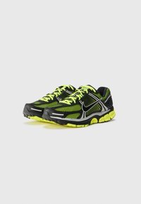 Zapatillas de running negras con detalles en amarillo neón, parte superior de malla, acentos reflectantes, cuello acolchado y suela de goma texturizada.