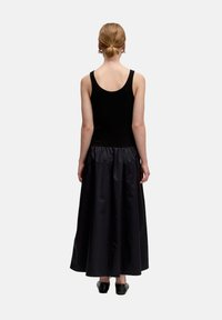 Zwarte tanktop met een aangesloten lijfje, gecombineerd met een lange, vloeiende zwarte satijnen rok. Glad textuur, minimalistisch ontwerp en enkel-lang.