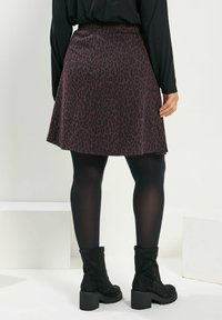 Hame simmaroita mustasta ja burgundista leoparditulpasta, jossa on elastinen vyötärö, levenevä muoto, teksturoitu kangas. Yhdistettynä mustiin legginsseihin ja nilkkabootseihin.